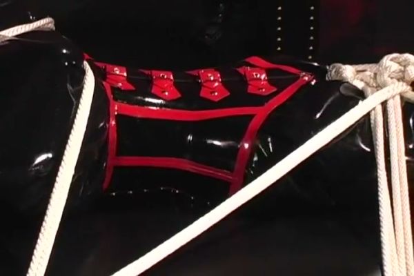 Black and red latex bondage session with restraints and rope harness on breastful.com