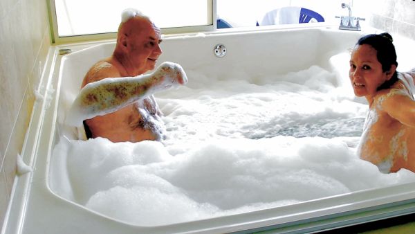 Slovakian woman and older man share a foamy nude bath in sunlit bathroom on breastful.com