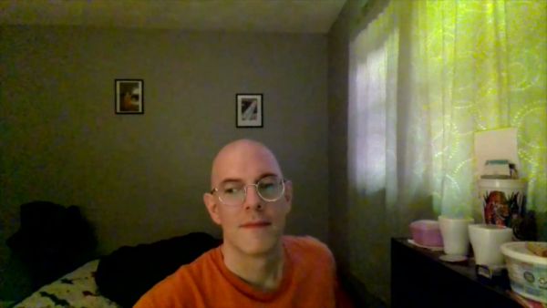 Bald man with glasses sits thoughtfully in a softly lit room on breastful.com