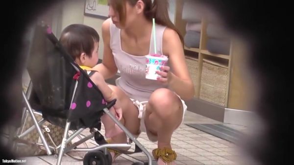 Young mom caught in white tank top as she bends over near her stroller on breastful.com