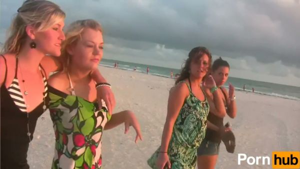 Two tan brunette women playfully expose themselves on a quiet beach on breastful.com