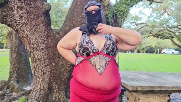 Curvy woman in red lingerie bends over picnic table in park on breastful.com