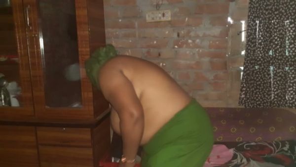 Green-haired stepmom bends over wooden cabinet in bedroom with brick wall on breastful.com