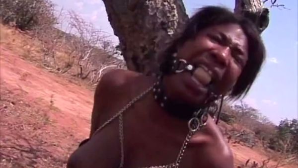 Dark-skinned woman submits to discipline in a leather harness during outdoor training session on breastful.com