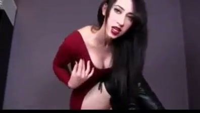 Confident woman in red dress gives herself a facial in a dark studio on breastful.com