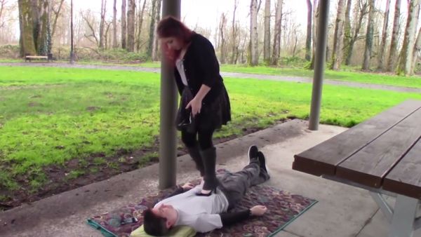 Redhead in heels dominates a man beneath her foot in the park on breastful.com