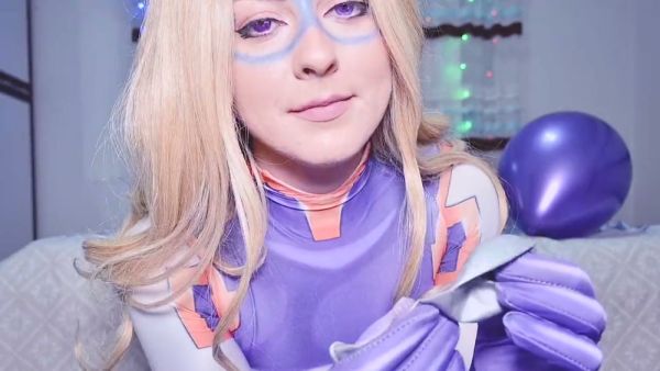 Blonde in purple latex superheroine costume plays with a silver balloon on a patterned bed - Japan - Poland on breastful.com