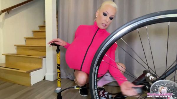 Blonde with inflatable breasts teases on a bike instead of fixing her tire on breastful.com