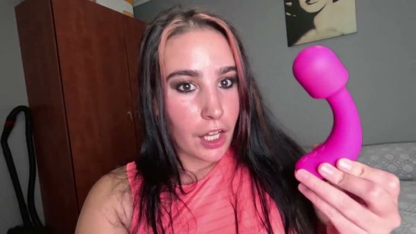 Curvy woman with black-pink hair explores her body with a pink vibrator in bed on breastful.com